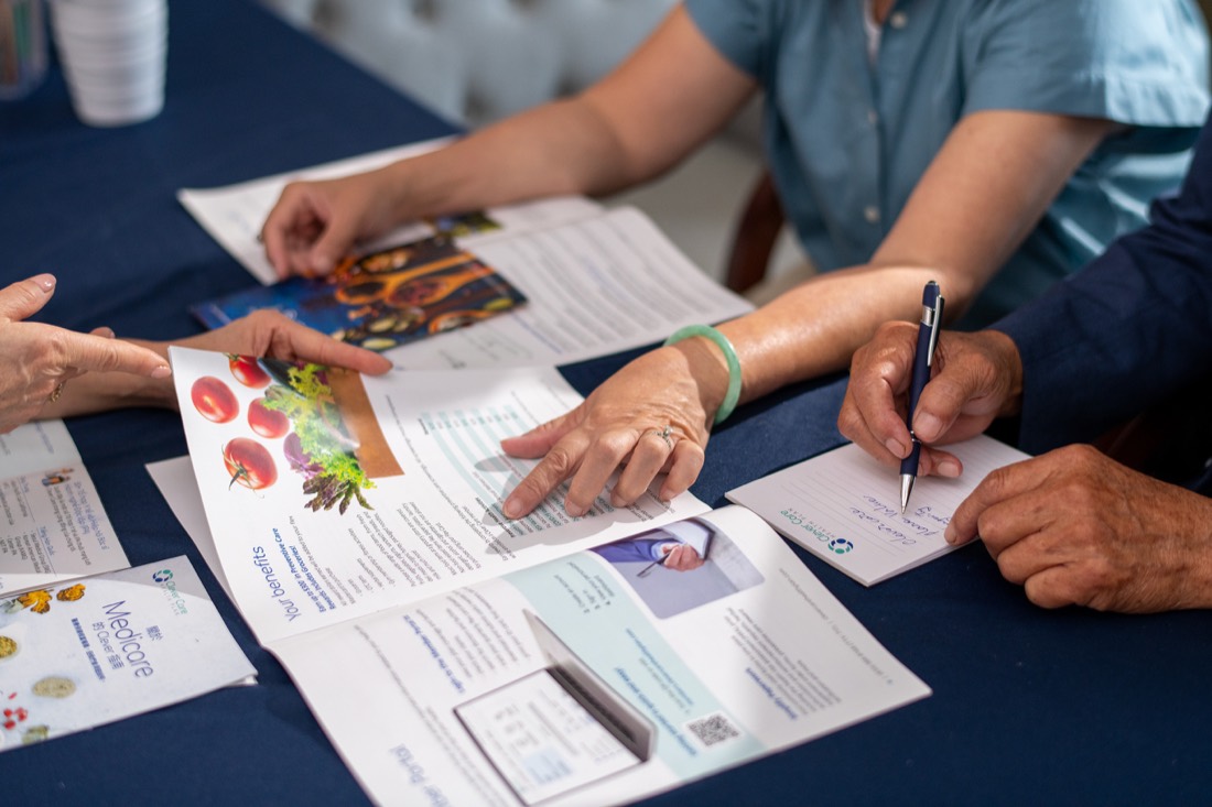 People reviewing printed Clever Care press materials at a table