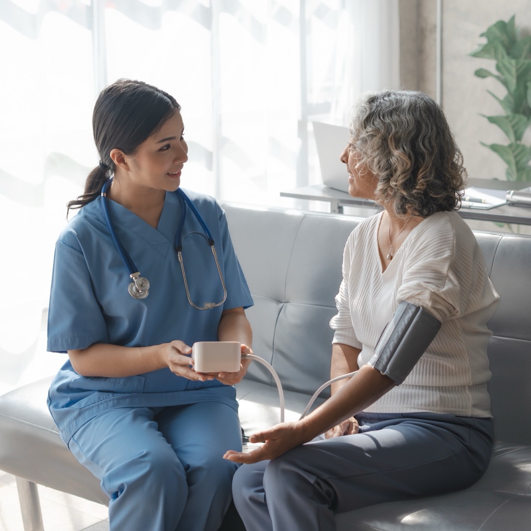 A nurse checking a senior patient's blood pressure at home